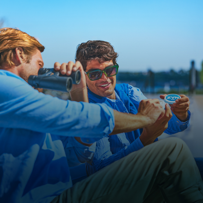 Two man outdoors holding a can of ZYN Cool Mint nicotine pouches.